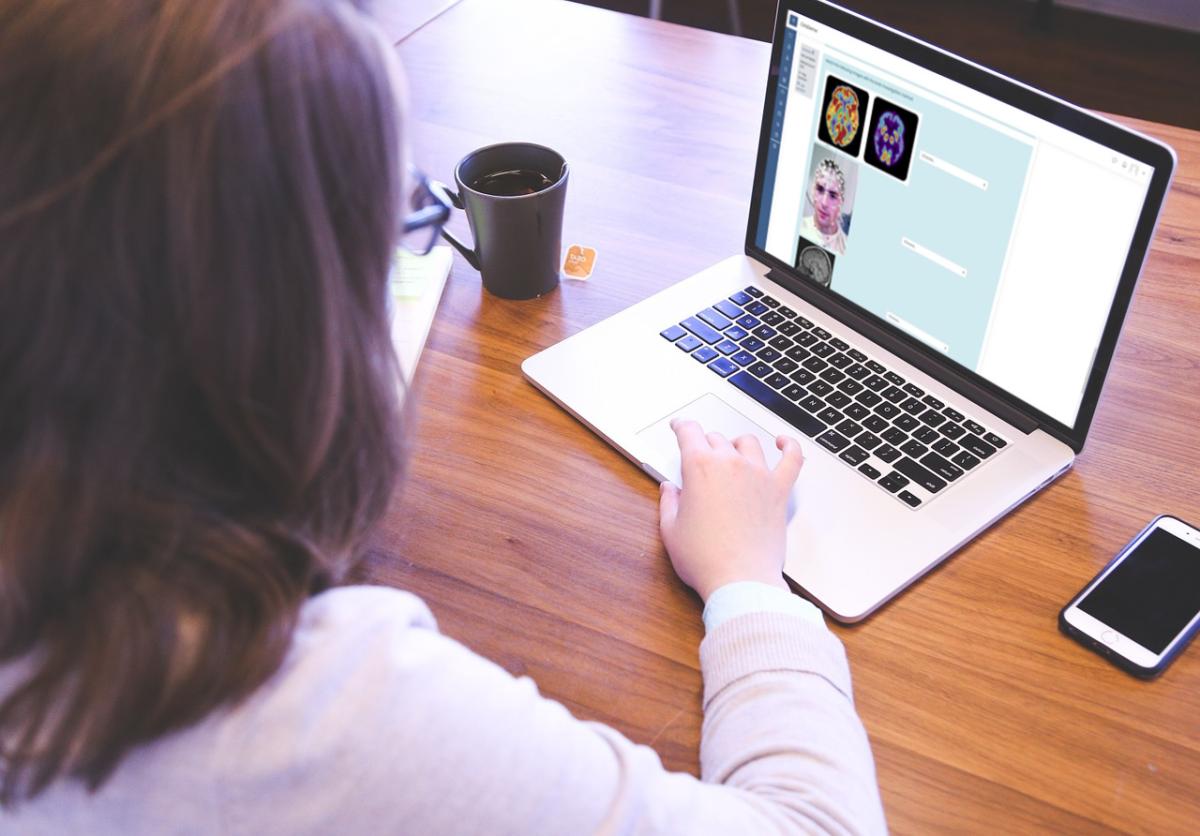 Person working on a laptop at a wooden desk with a smartphone and coffee.