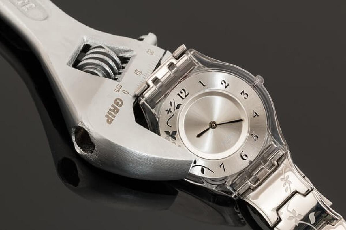 Wrench gripping a silver wristwatch on a black background.