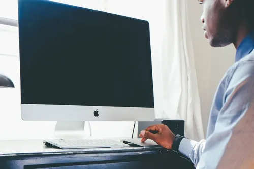 Man sitting at a desk using a desktop computer.